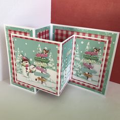 two christmas cards with snowmen and trees on them, one is folded to look like an open book