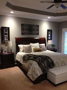 a bedroom with a bed, ottoman and ceiling fan