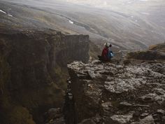 a person sitting on the edge of a cliff