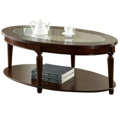 an oval coffee table with glass top and two books on the bottom, in front of a white background