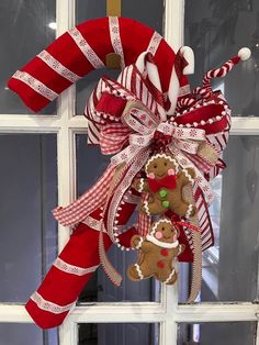 a red and white christmas wreath with a gingerbread door hanger on the front door