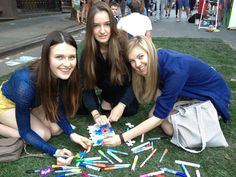 three girls are playing with crayons on the grass