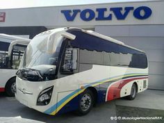 two buses parked in front of a volvo dealership