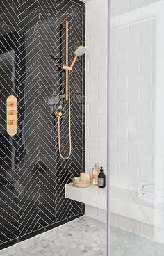 a black and white bathroom with herringbone tile on the shower wall, toiletries and soap