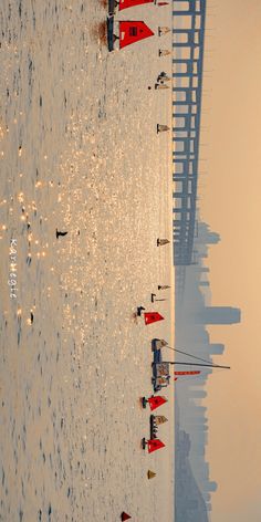 the beach is lined with red buoys and people are standing in the shallow water