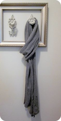 a towel hanging on the wall in front of a framed photo and an owl sculpture