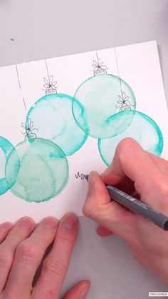 someone is drawing christmas ornaments on paper