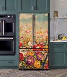 a painting on the side of a refrigerator in a kitchen with green cabinets and wood flooring