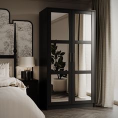 a bed sitting next to a tall black cabinet with mirrors on it's sides