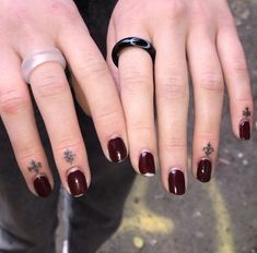 a woman's hand with two rings on her fingers and one ring has crosses tattooed on it