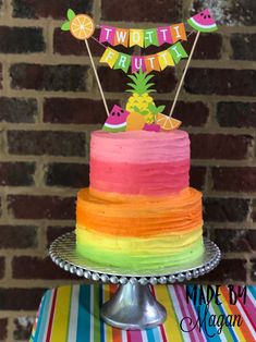 a multi - colored cake with pineapples and watermelon on top is sitting on a table