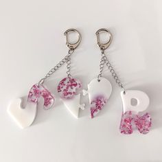 three pieces of heart shaped key chains with pink and white designs hanging from each other