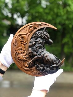 a person holding up a carved wooden plaque with a wolf on it's face