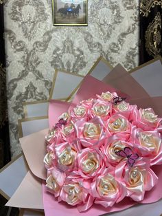 a bouquet of pink and white roses on top of a table next to wallpaper