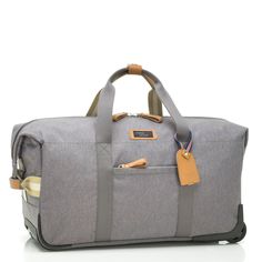 a grey duffel bag with brown handles and two compartments on the front, sitting on a white surface