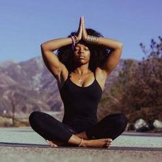 a woman sitting in the middle of a yoga pose with her hands behind her head