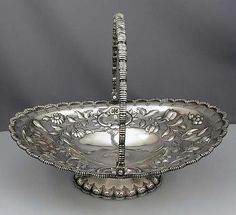 an ornate silver bowl with handles and beaded decoration on the rim is shown in front of a gray background