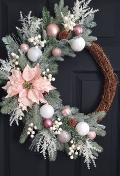 a christmas wreath with poinsettis and pine cones hanging on a black door