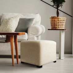 a living room with a white couch, chair and plant on the table next to it