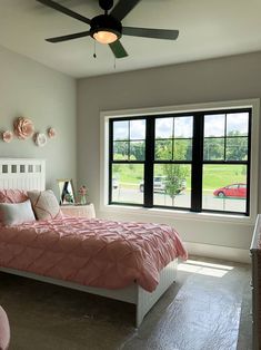 a bed room with a neatly made bed and a large window overlooking the field outside