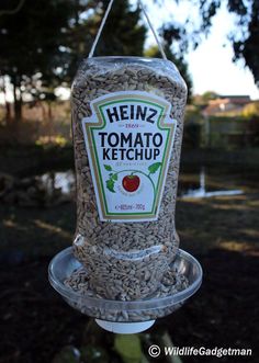 a bird feeder with seeds hanging from it's side and the words heinzz tomato ketchup on top