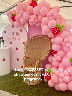 a chair made out of balloons and strawberries is sitting in front of a display