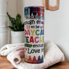 a colorful coffee mug sitting on top of a wooden table next to a white towel