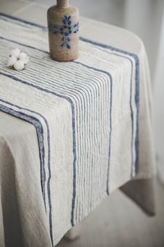 a small bottle sitting on top of a table next to a piece of cloth with flowers in it