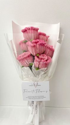 a bouquet of pink flowers is wrapped in white paper