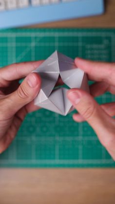 two hands are holding an origami piece