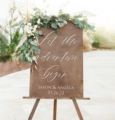 a wooden sign with greenery on it that says let the adventure begin