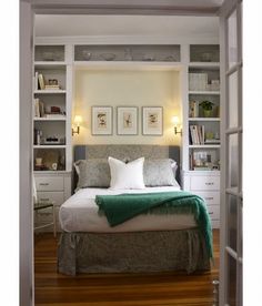 a bed sitting in the middle of a bedroom next to a book shelf filled with books