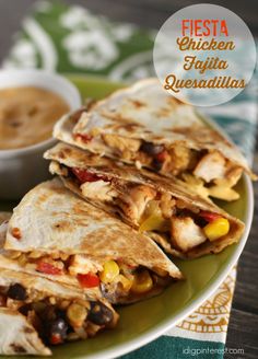 three quesadillas on a green plate with a bowl of salsa in the background