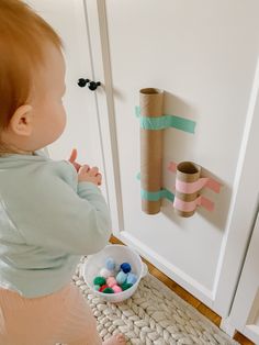 a baby standing in front of a toilet paper roll