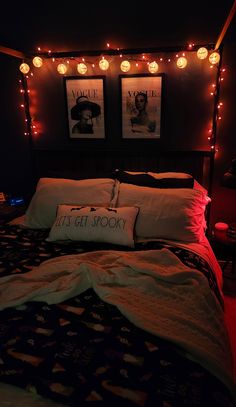 a bed with two pictures on the wall above it and lights hanging from the headboard