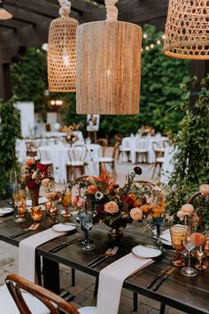 an outdoor dining area with tables, chairs and hanging lights in the middle of it