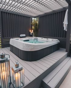 a hot tub sitting on top of a wooden deck next to two lamps and lanterns