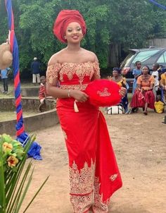 a woman in a red and gold dress is holding a heart shaped pillow while people watch