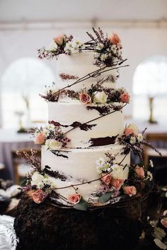 a wedding cake with flowers and branches on the top is displayed in front of an audience