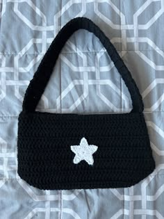 a crocheted bag with a white star on it sitting on top of a bed