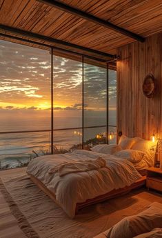 a large bed sitting in a bedroom next to a window with the sun going down