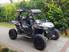 a polaris rzr xp4 is parked in front of some bushes