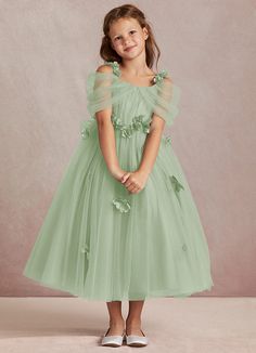 Shaylee is an enchanting A-line flower girl dress that is crafted from delicate tulle. She features intricately handmade 3D flower embellishments. Off-shoulder sleeves offer a touch of whimsy that is complimented with a tulle bow back. The flowers cascade gracefully down the tulle skirt that flows with every step. Green Ball Dresses, Off The Shoulder Tulle Dress, Sage Green Flower Girl Dress, Sage Flower Girl Dress, Lavender Flower Girl Dress, Pastel Green Dress, Green Flower Girl Dresses, Light Green Dress, Sage Green Bridesmaid Dress