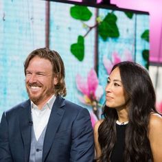 two people sitting next to each other in front of a tv screen with flowers on it