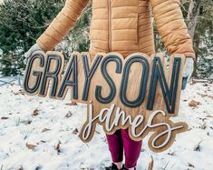 a person standing in the snow holding a grayson game sign