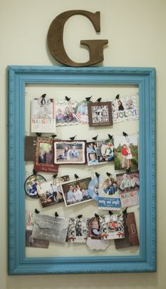 a blue frame with pictures and magnets on it is hanging on the wall next to a sign that says g