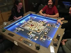 three people sitting at a table with a board game in front of them on it