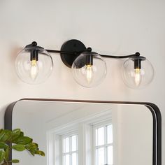 a bathroom vanity light with three bulbs on the wall and a mirror in front of it