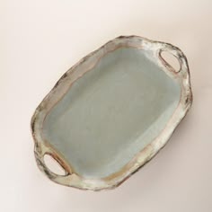 a white ceramic dish with holes in the middle on a pink wall behind it is an oval shaped object