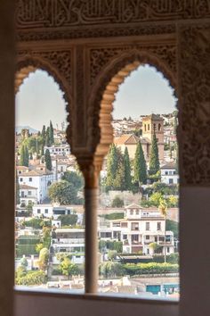 the view from inside an ornate building looking out onto a city with lots of trees